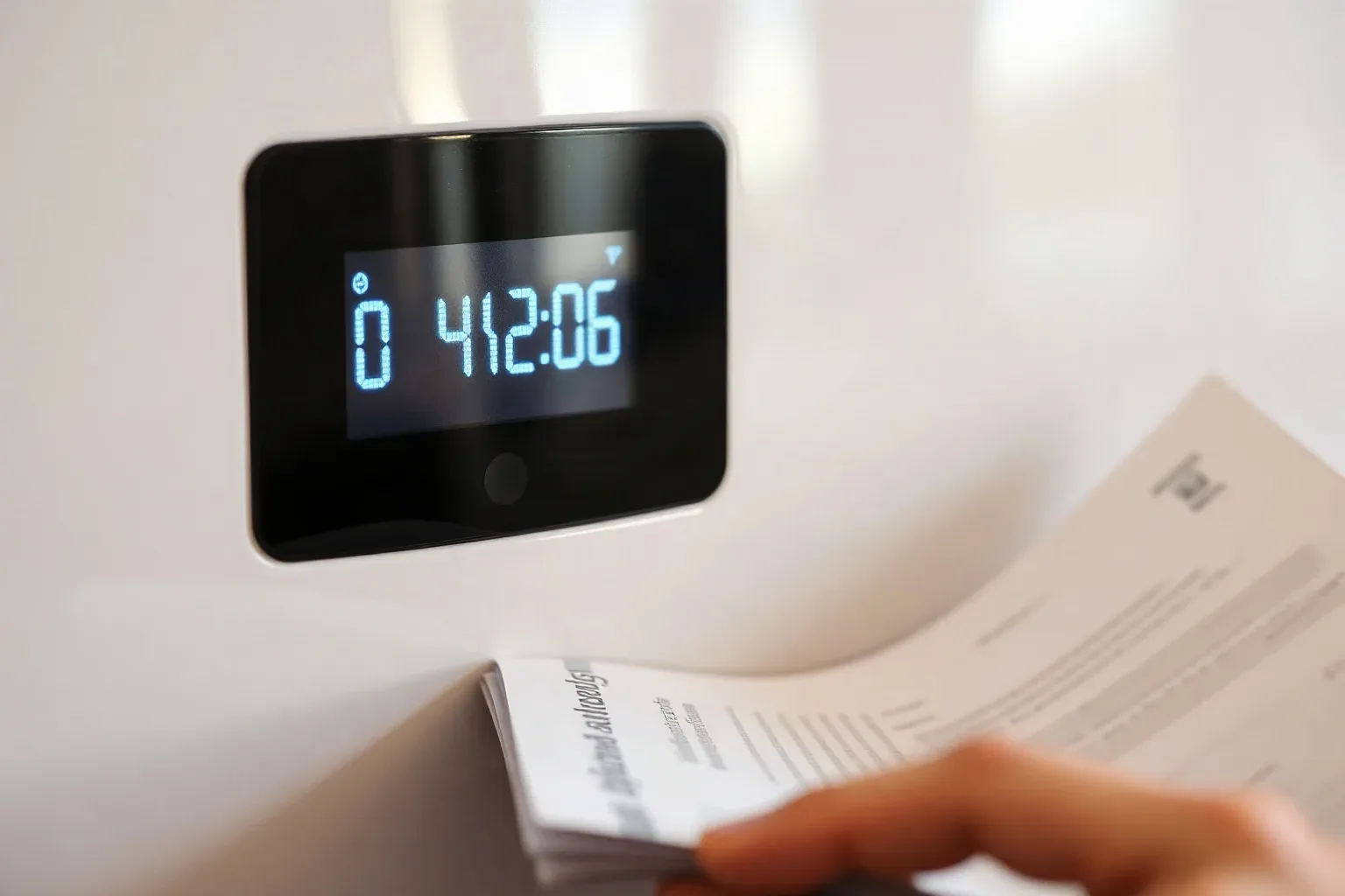 A close-up of a boiler LCD screen displaying an alphanumeric fault code with the manual open beside it